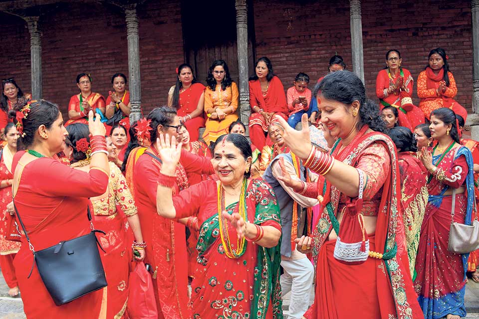 Women in red saris singing during Teej